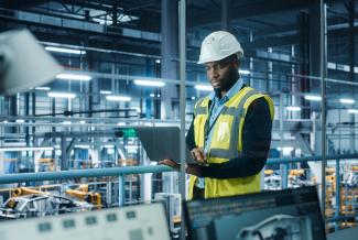 Manufacturer with Laptop on Plant Floor